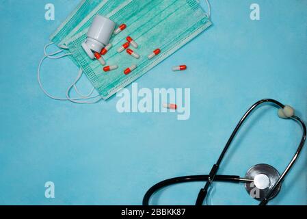 Maschera medicale monouso, compresse, stetoscopio su sfondo blu. Foto Stock