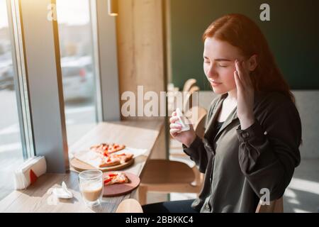 Il modello femminile tiene sopra alla sua testa e chiude gli occhi. La giovane donna sente mal di testa. Foto Stock