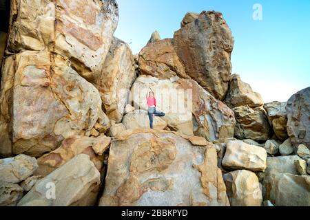 Hang Rai Coast, Ninh Thuan Province, Vietnam - 13 marzo 2020: Immagine di un turista femminile che pratica il suddetto yoga muove grandi massi a Hang R. Foto Stock