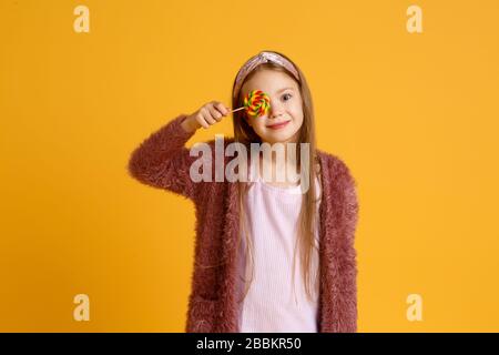 Bambina godere lollipop durante la pausa scolastica. Buon piccolo scolaretto mangiare lecca lecca. Ampie lollipop a vortice sulle avambracci Foto Stock