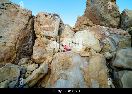 Hang Rai Coast, Ninh Thuan Province, Vietnam - 13 marzo 2020: Immagine di un turista femminile che pratica il suddetto yoga muove grandi massi a Hang R. Foto Stock