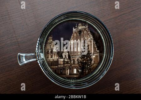 Vista superiore della tazza di caffè sul tavolo con la Casa delle teste nere con albero di Natale di notte in riflessione, la città vecchia riga, Lettonia Foto Stock