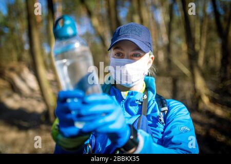 Ecologo prelievo di campioni d'acqua da una fonte naturale in guanti protettivi e maschera Foto Stock