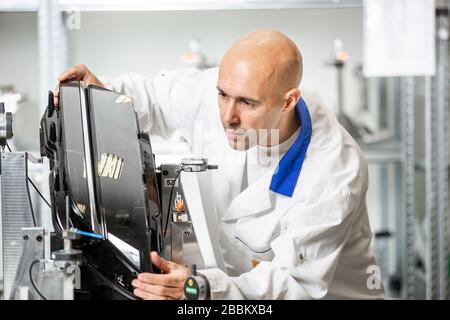 Ingegnere di qualità, metrologo che misura alcuni stampi in plastica su un calibro professionale, maschera, concetto industriale Foto Stock