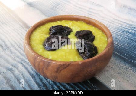 Farinata d'avena con curcuma e prugne su sfondo di legno Foto Stock