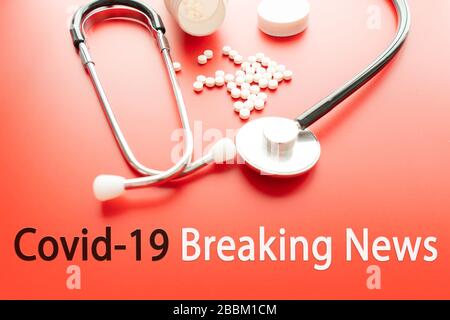 COVID 19 BREAKING NEWS text with stetoscope and glosing glass on red background. Covid-19 o Coronavirus Concept Foto Stock