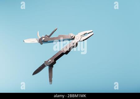 Lo strumento multifunzione multitool si trova su uno sfondo blu. Il concetto di un multi-utensile espanso con spazio libero. Foto Stock