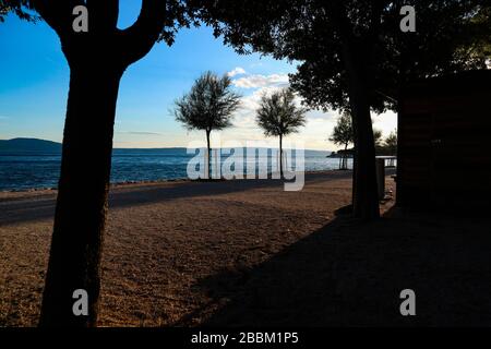 Godendo dei raggi del sole dorati al tramonto mentre camminate sulla spiaggia di sabbia croata a Novi Vinodolski Foto Stock