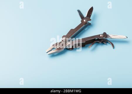 Lo strumento multifunzione multitool si trova su uno sfondo blu. Il concetto di un multi-utensile espanso con spazio libero. Foto Stock