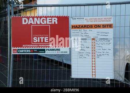 Pericolo, pericoli sul posto e segnali di salute e sicurezza su una recinzione metallica all'esterno di un edificio a St. Heliers, Auckland, Nuova Zelanda. Foto Stock