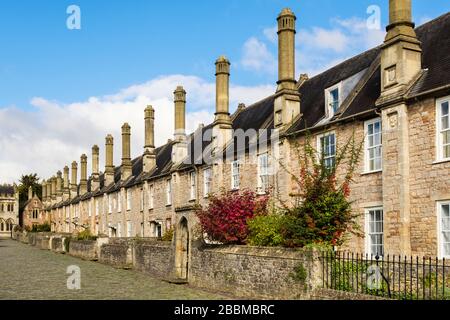 Riga del XIV secolo case a schiera con alte ciminiere e piccoli giardini fronte sulla strada di ciottoli in Vicari vicino, pozzi, Mendip, Somerset, Inghilterra, Regno Unito Foto Stock