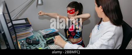 Donna che telelavorava e guarda con sua figlia Foto Stock