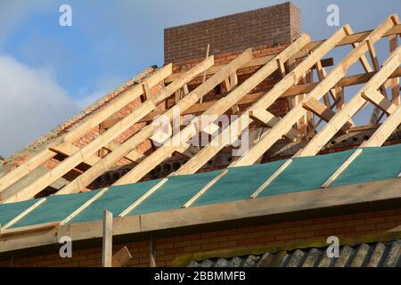 Costruzione di una struttura in legno sul tetto della casa. Costruzione di tetti incompleta casa tralicci tetto, barriera al vapore, travi in legno, eaves, legname. Foto Stock