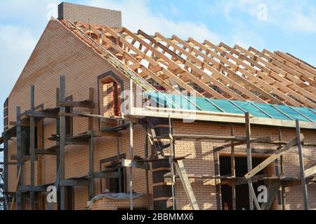 Costruzione di una struttura in legno sul tetto della casa. Costruzione di tetti incompleta casa tralicci tetto, barriera al vapore, travi in legno, eaves, legname Foto Stock