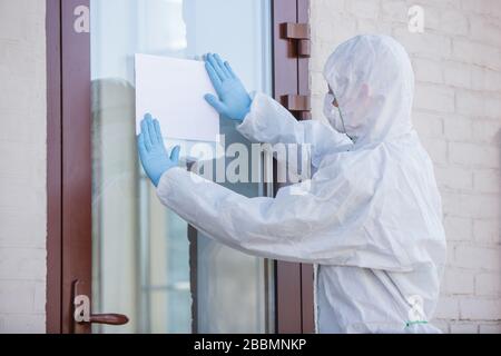 Coronavirus pandemico. Disinfettore in tuta protettiva e maschera che fa il segno di avvertimento, copyspace. Malattia di COVID-19 dell'agsyst di protezione. Prevenzione della diffusione del virus della polmonite con le superfici. Foto Stock