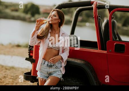 Bella giovane donna che si rilassa in auto sul lago Foto Stock