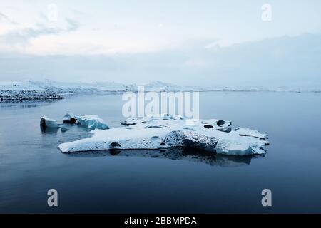 Un piccolo iceberg galleggia verso il mare calato da un ghiacciaio interno. Foto Stock