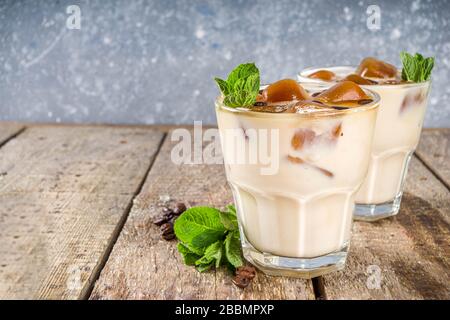 Caffè freddo estivo, latte, frittata, frappuccino. Caffè cocktail ghiacciato con cubetti di ghiaccio di caffè ghiacciato, latte o latte non caseario e foglie di menta. Woode Foto Stock