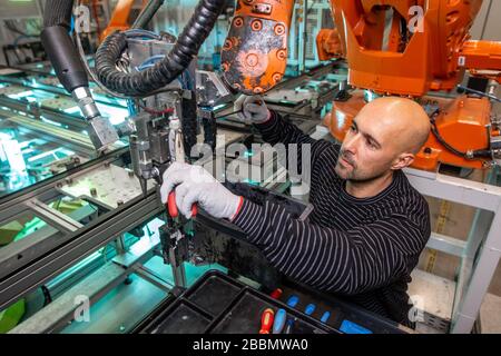 Ingegnere che esegue la manutenzione su bracci robot automatici in fabbrica intelligente e industriale automobilistica Foto Stock