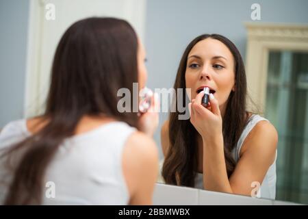Giovane donna è il rossetto in bagno. Foto Stock