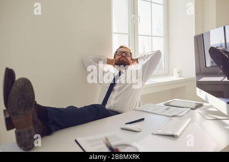 L'uomo d'affari riposa meditando i sogni sul posto di lavoro al tavolo con un computer in ufficio Foto Stock