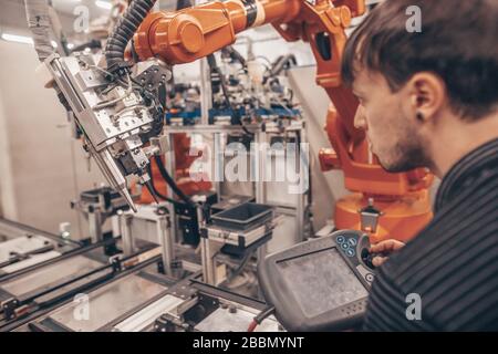 Ingegnere, tecnico che lavora con robot automatico nel settore automobilistico industriale, fabbrica intelligente, luogo di lavoro automatizzato Foto Stock