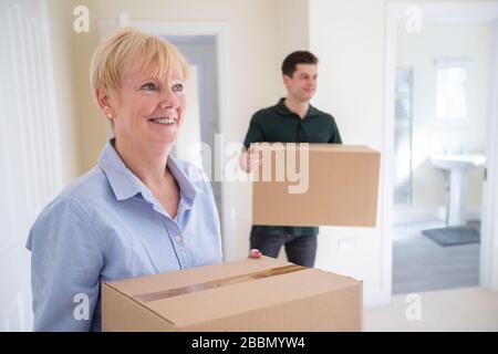 Donna anziano downsizing in scatole di trasporto di pensione in Nuova Casa in giorno commovente con l'aiuto dell'uomo di rimozione Foto Stock