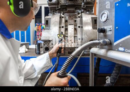 Ingegnere che esegue la manutenzione su uno stampo di iniezione per componenti in plastica, concetto industriale e automobilistico Foto Stock