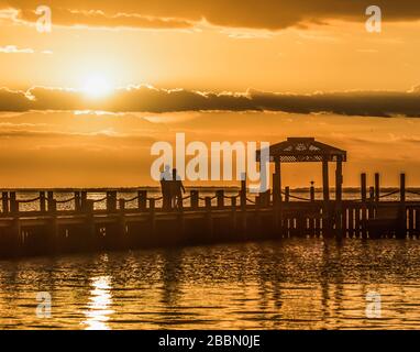 Una coppia gode del tramonto vicino ad un gazebo che si affaccia sulla Baia di Barnegat sull'Isola di Long Beach Foto Stock