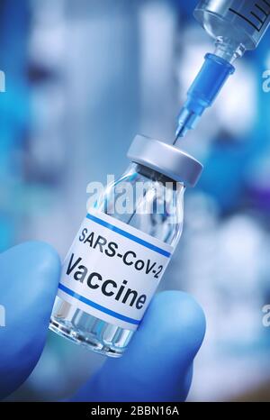 guanti di gomma blu con dita che tengono un flaconcino di vaccino e una siringa Foto Stock