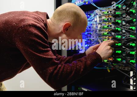 Tecnico del centro dati MAN che esegue la manutenzione del server. Sostituzione dei cavi, Foto Stock