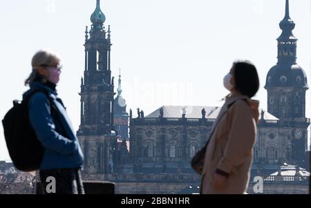 Dresda, Germania. 01st Apr, 2020. Due donne indossano maschere facciali e stanno chiacchierando nel giardino del Palazzo Giapponese, sullo sfondo si può vedere la Chiesa della Corte (l-r), la Chiesa della Croce e l'Hausmannsturm. Il nuovo coronavirus viene trasmesso principalmente mediante infezione da goccioline. Credito: Robert Michael/dpa-Zentralbild/dpa/Alamy Live News Foto Stock