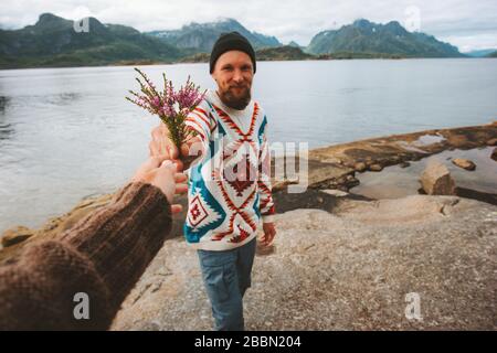 Romantica coppia all'aperto uomo che dà fiori bouquet amore relazione lifestyle viaggio vacanze all'aperto camminare insieme sulla spiaggia in Norvegia Foto Stock