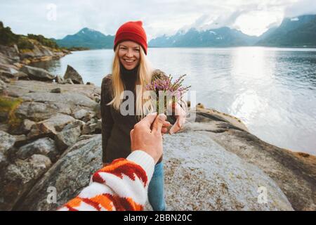 Coppia in amore mano dell'uomo che dà fiori di bouquet alla donna stile di vita di viaggio vacanze romantiche in Norvegia rapporto sentimenti concetto Foto Stock