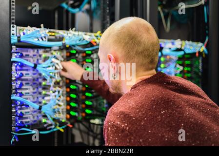 Tecnico del centro dati MAN che esegue la manutenzione del server. Sostituzione dei cavi, Foto Stock