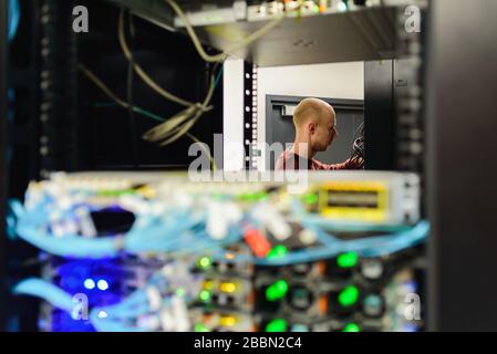 Tecnico del centro dati MAN che esegue la manutenzione del server. Sostituzione dei cavi, Foto Stock