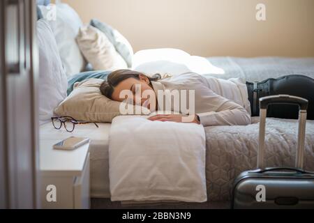 Una donna d'affari stanca dorme vestita in camera d'albergo. Foto Stock