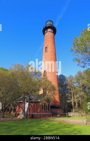 La struttura in mattoni rossi del Faro di Currituck Beach sorge sopra una piccola casa d'ingresso e pini al Currituck Heritage Park vicino a Corolla, N. Foto Stock