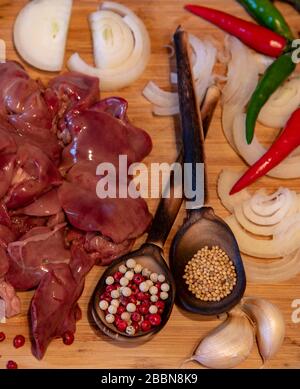 Fegato di pollo crudo e varie spezie sul tagliante Foto Stock