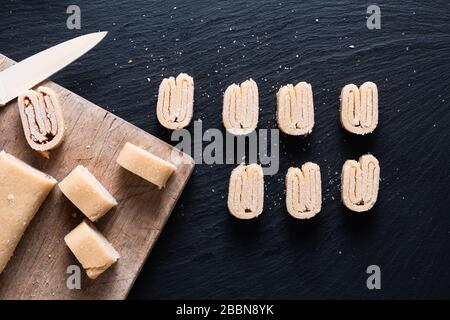 Concetto di cibo fatto in casa pasta di pasta di pasta di pasta di pasta di pasta biologica cruda per i vagli francesi, pasticceria cinese di farfalla o pasta di orecchie di elefante su tavola di ardesia nera Foto Stock