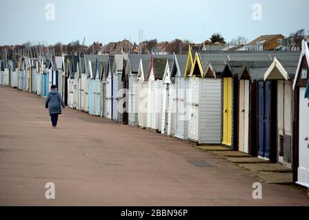 Una donna cammina oltre le capanne sulla passeggiata a Southend, Essex, come il Regno Unito continua in blocco per aiutare a frenare la diffusione del coronavirus. Foto Stock