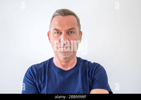 Intenso uomo di mezza età focalizzato con espressione seria e determinata che vede la fotocamera in un ritratto della testa e delle spalle su bianco con spazio di copia Foto Stock