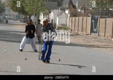 Ragazzi che giocano a cricket per strada a Karachi Foto Stock