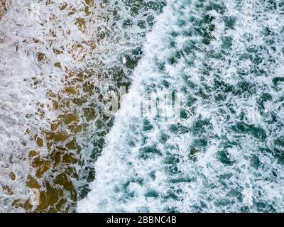 Vista aerea con droni delle onde oceaniche che si infrangono sulla costa tropicale di Bali, Indonesia Foto Stock