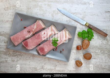 fette di prosciutto arrotolate con erbe su un tavolo Foto Stock