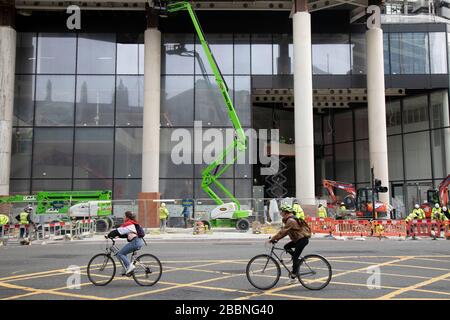 I lavoratori che lavorano in alto su un selezionatore di ciliegie sul più recente grattacielo della città di Londra, come ciclisti passano il 7th marzo 2020 a Londra, Regno Unito. Man mano che il distretto finanziario cresce in altezza, l'architettura ha cambiato il volto di Londra con molte aziende diverse che occupano i vari piani e livelli, alcune delle quali rimangono vuote come investimenti esteri. Foto Stock