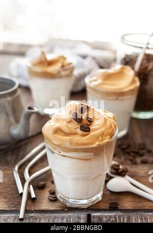 Caffè montato in un bicchiere con chicchi di caffè Foto Stock