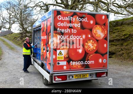 Tesco food van driver consegna generi alimentari in sacchetti di plastica a una casa del cliente nel Galles rurale durante la pandemia di Coronavirus Covid-19 Galles UK 2020 Foto Stock