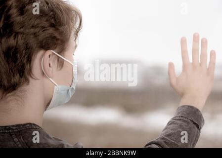 Ragazzo in maschera vicino alla finestra Foto Stock