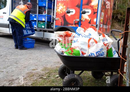 Tesco food van driver consegna generi alimentari in sacchetti di plastica a una persona più anziana auto-isolante nel Galles rurale durante il Coronavirus Wales UK 2020 Foto Stock